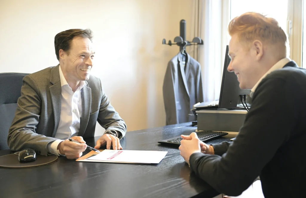Zwei Männer besprechen an einem Schreibtisch im Büro gemeinsam Unterlagen