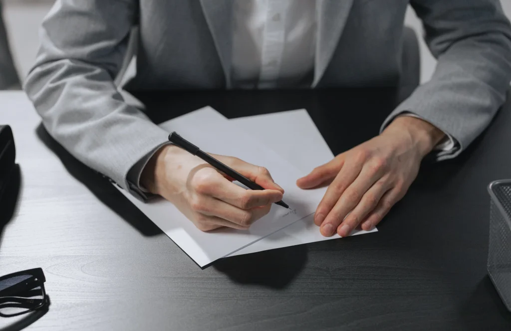 Hand unterschreibt ein Schreiben an einem Schreibtisch